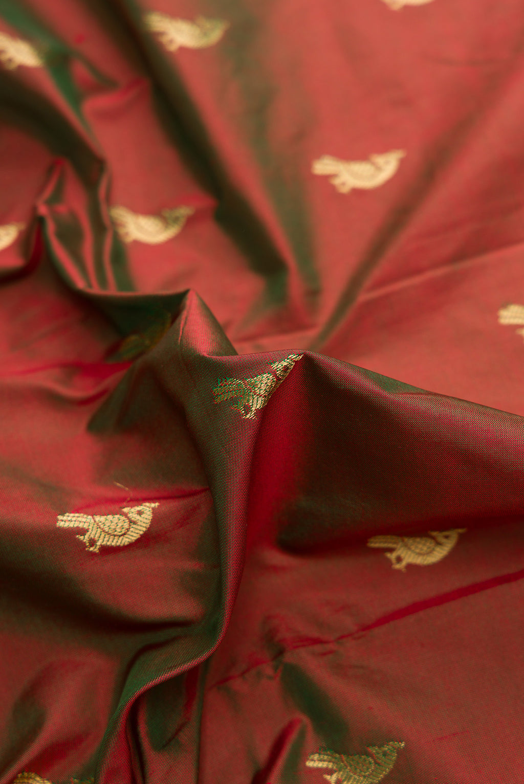 Close up of Green with Red Color Paithani Silk Saree with Zari Butta on the body and Paithani Border.  displaying folds