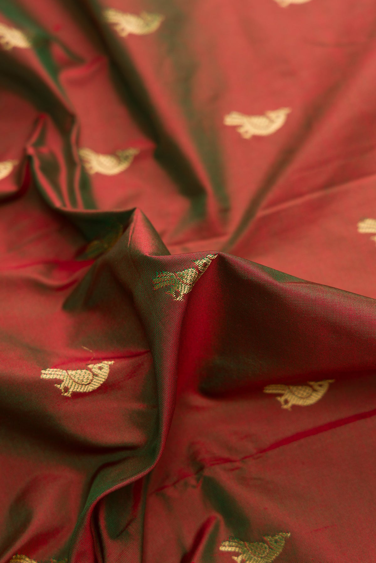 Close up of Green with Red Color Paithani Silk Saree with Zari Butta on the body and Paithani Border.  displaying folds