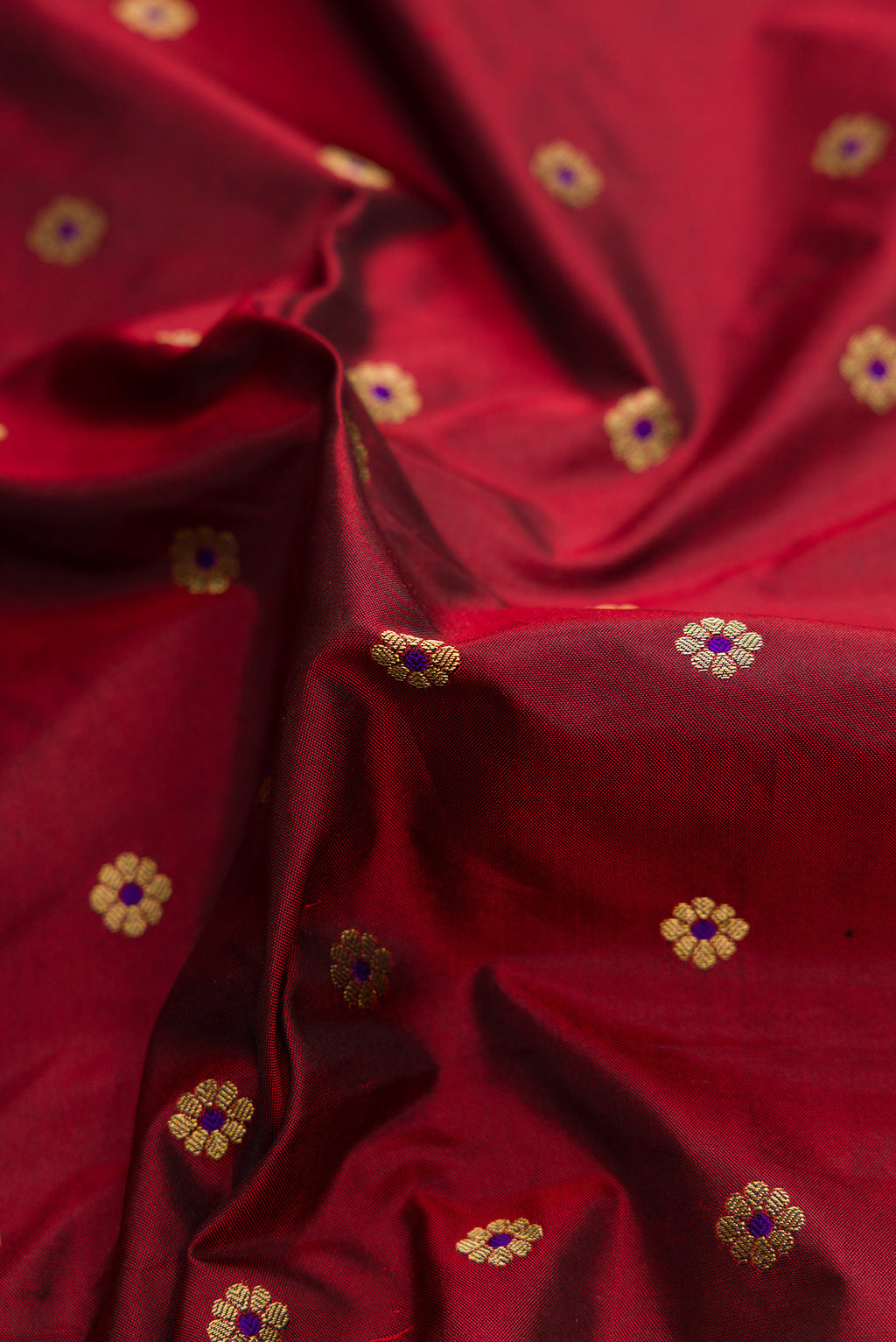 Close up of Maroon Paithani Silk Saree with Zari Butta on the body and Paithani Border.  displaying folds