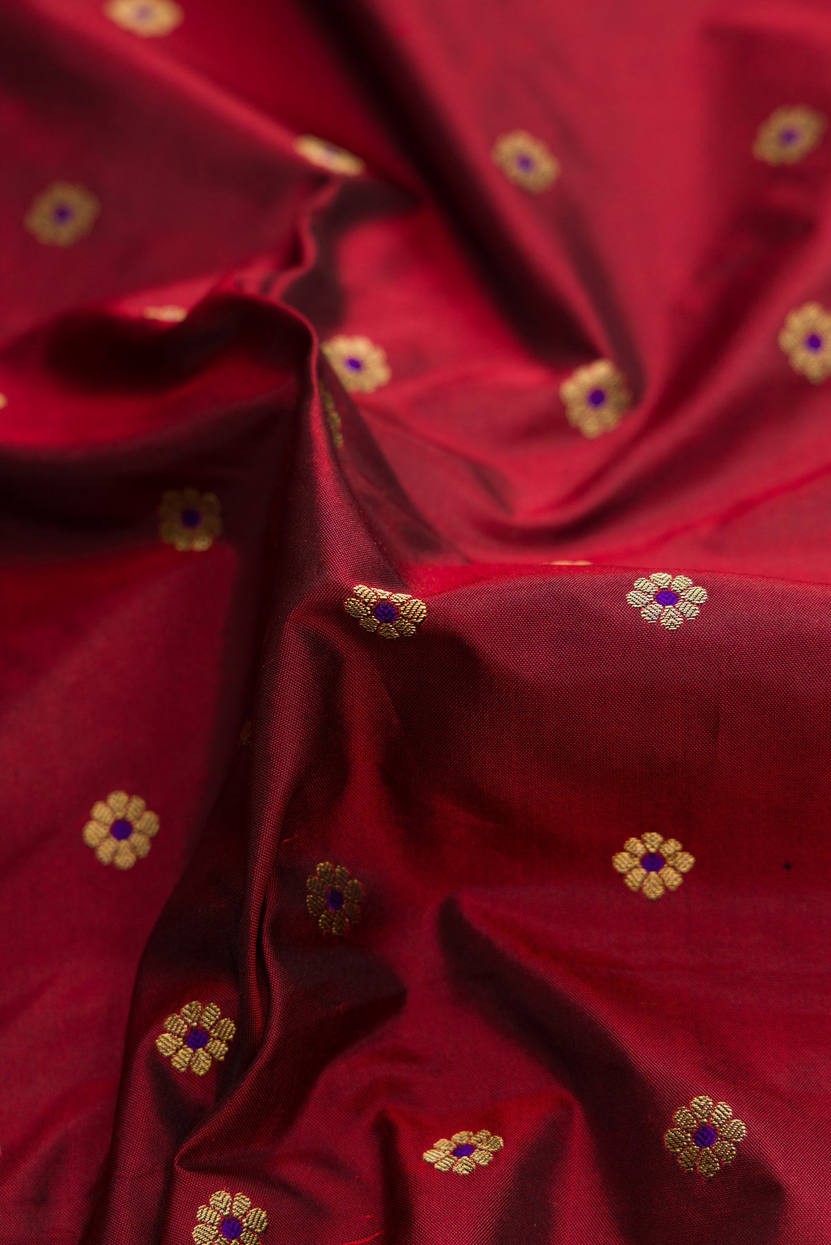 Close up of Maroon Paithani Silk Saree with Zari Butta on the body and Paithani Border.  displaying folds