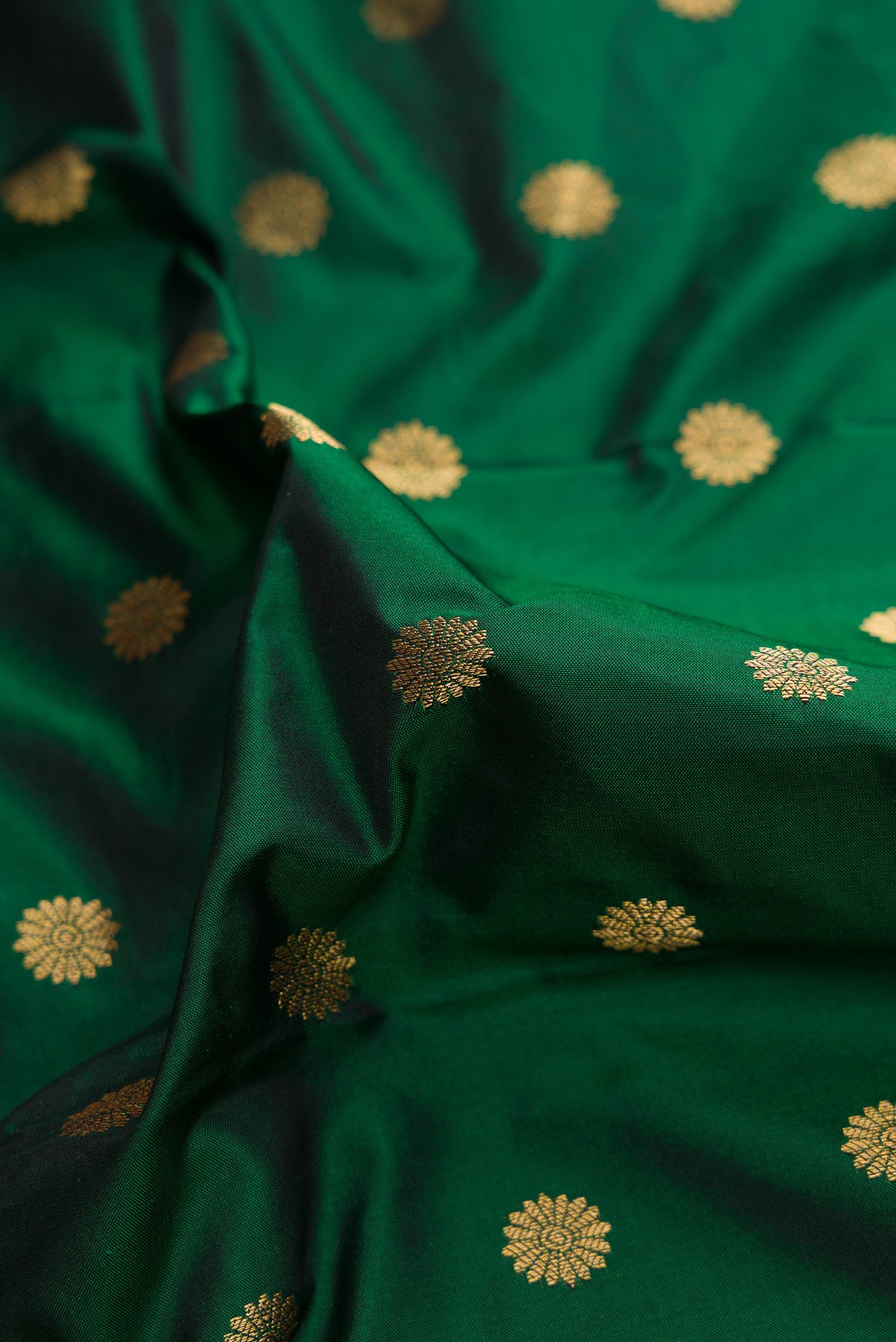 Close up of Bottle Green Paithani Silk Saree with Zari Butta on the body and Paithani Border.  displaying folds