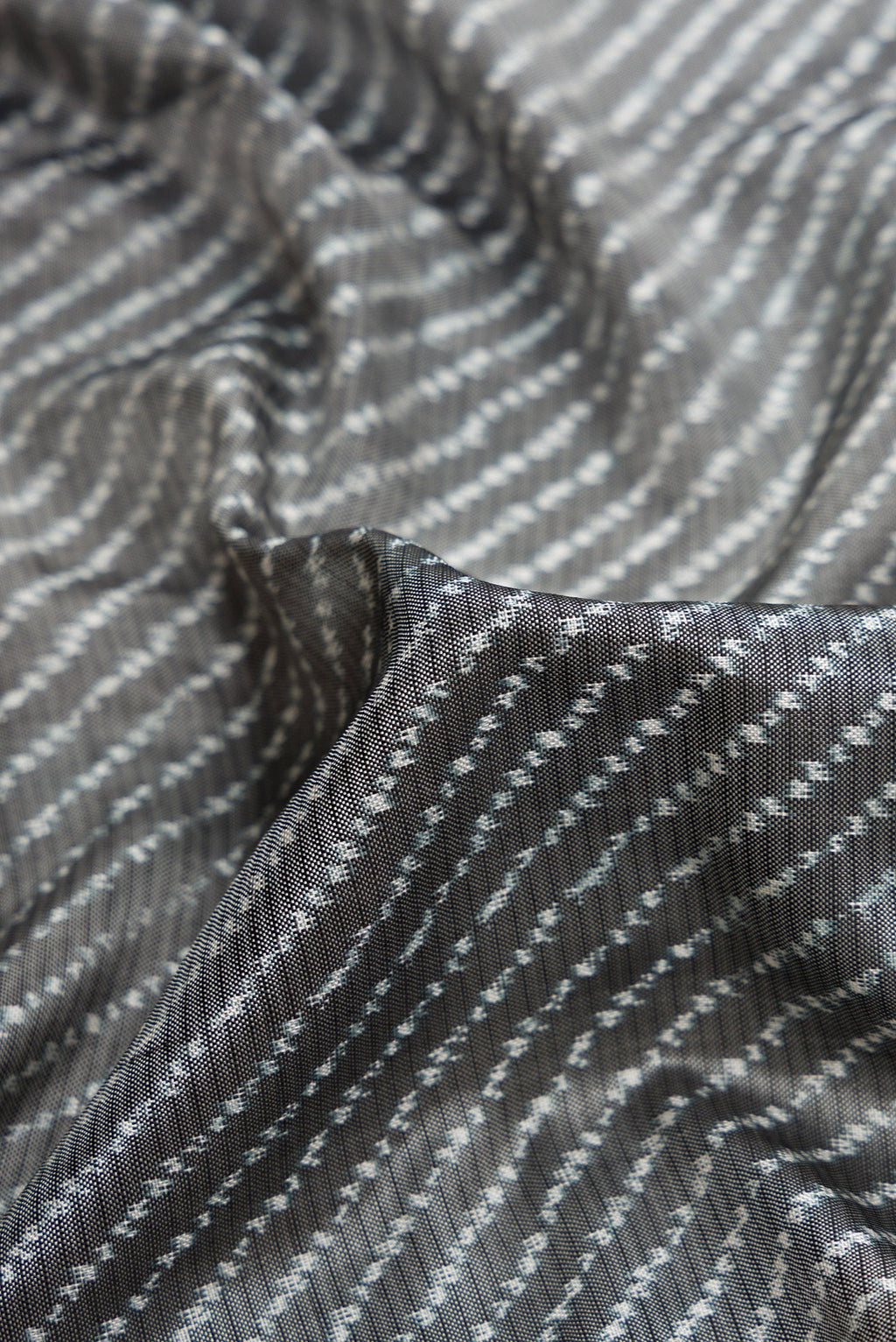 Close up of Grey Dual Tone Double Ikat Saree with Ikat Print on the body and Ikat Border.  displaying folds