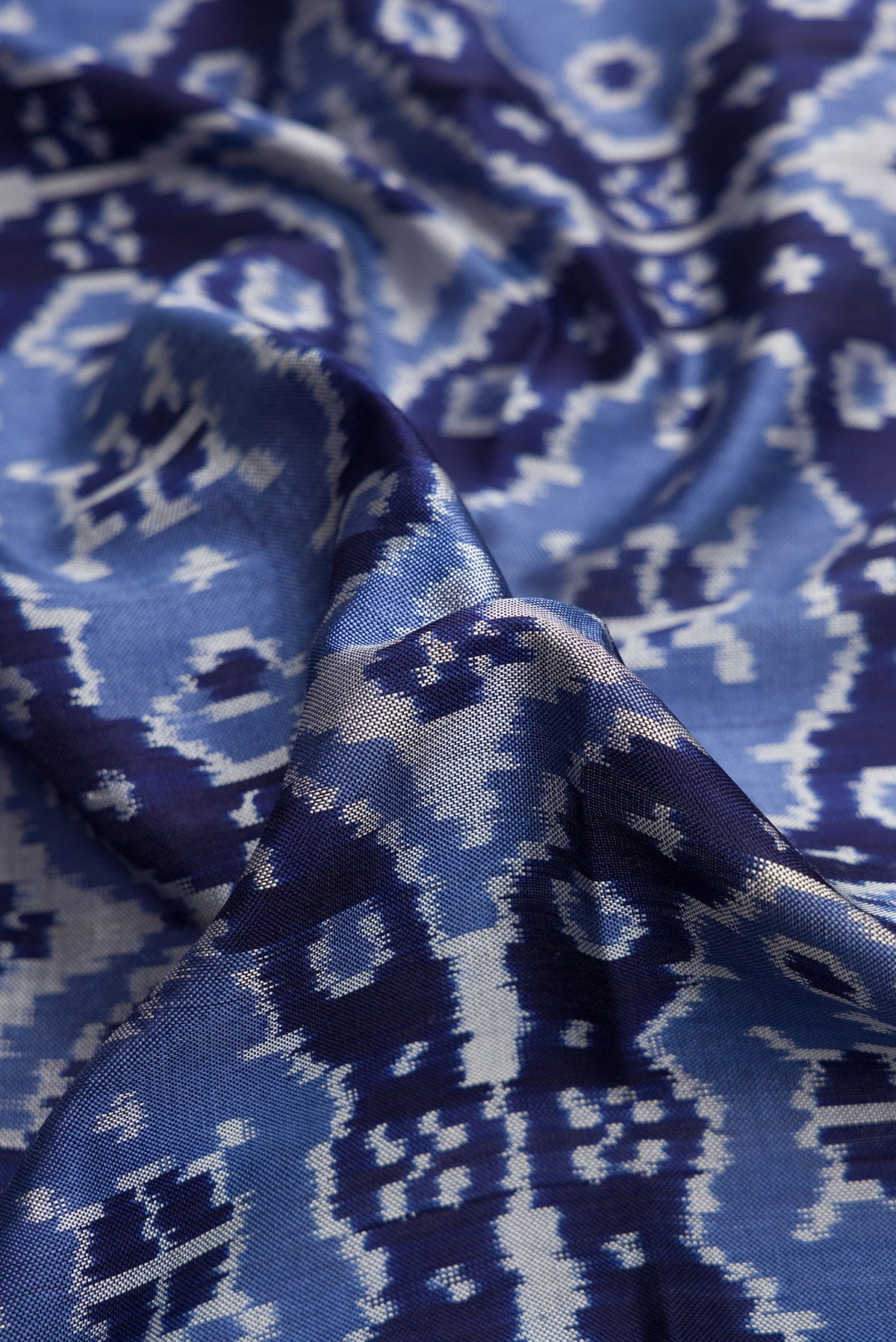 Close up of Navy Blue Dual Tone Double Ikat Saree with Ikat Print on the body and Plain Border.  displaying folds