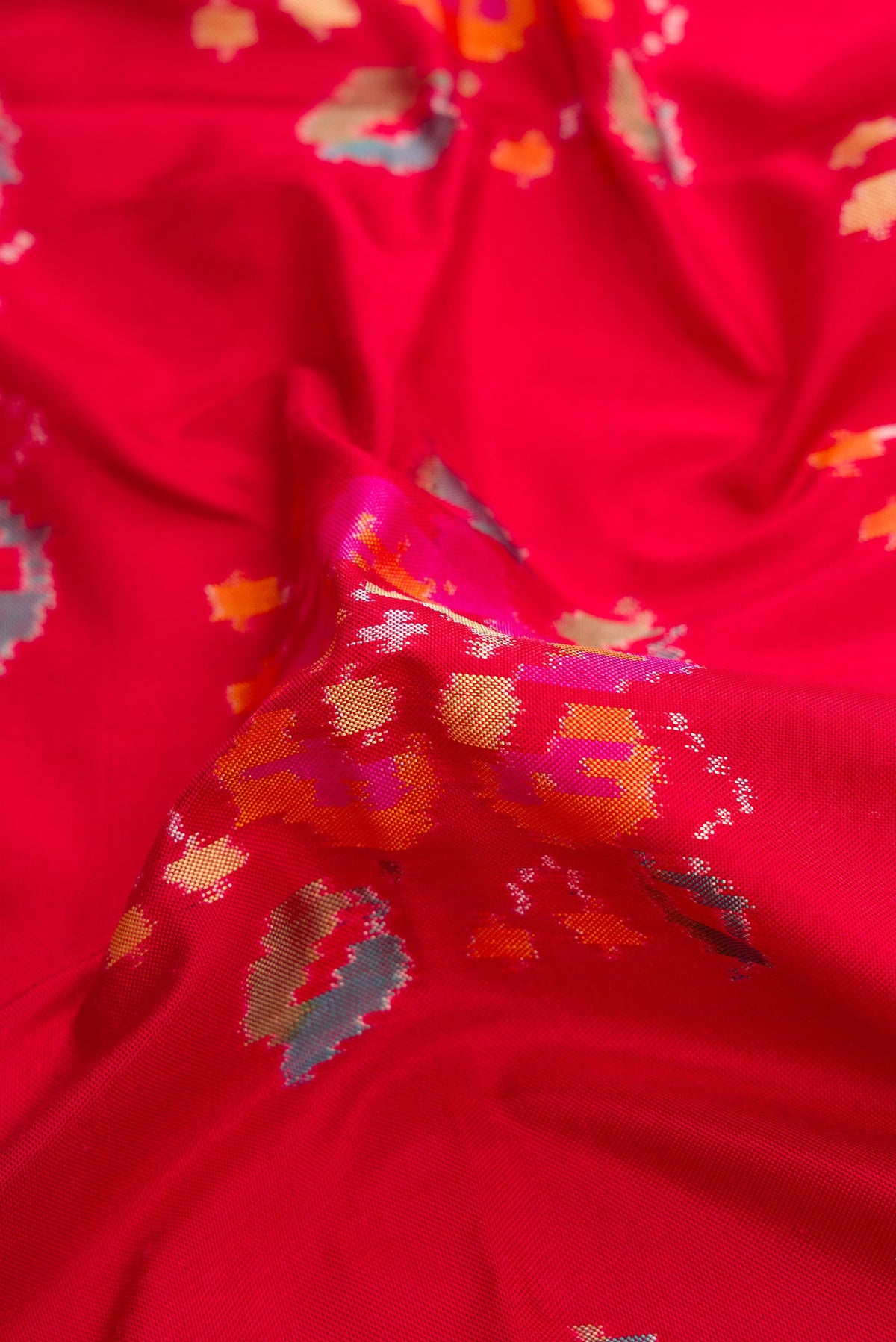 Close up of Red Dual Tone Double Ikat Saree with Ikat Print on the body and Zari Border.  displaying folds