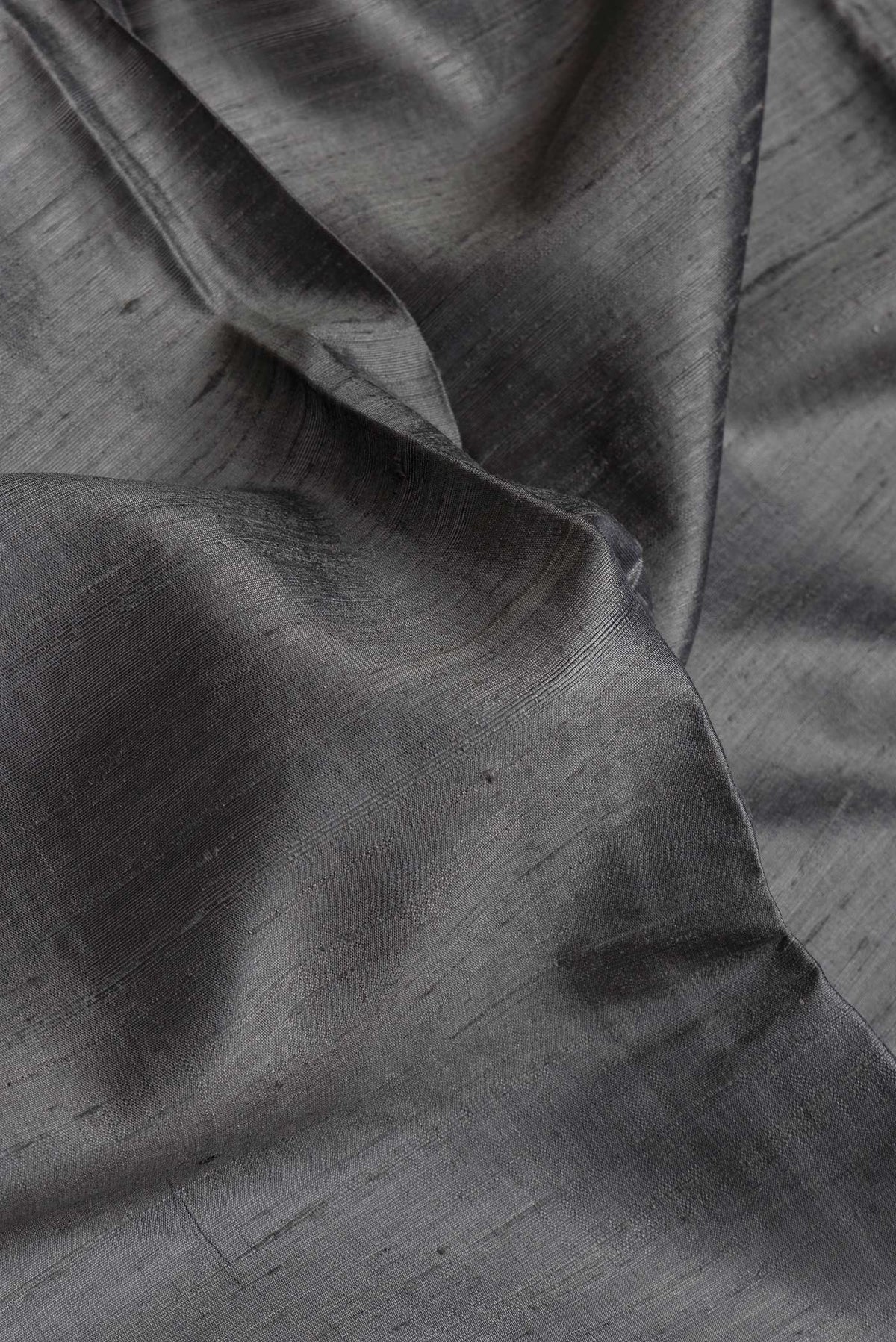 Close up of Grey Dual Tone Raw Silk Saree with Plain Body and Thin Zari Line.  displaying folds