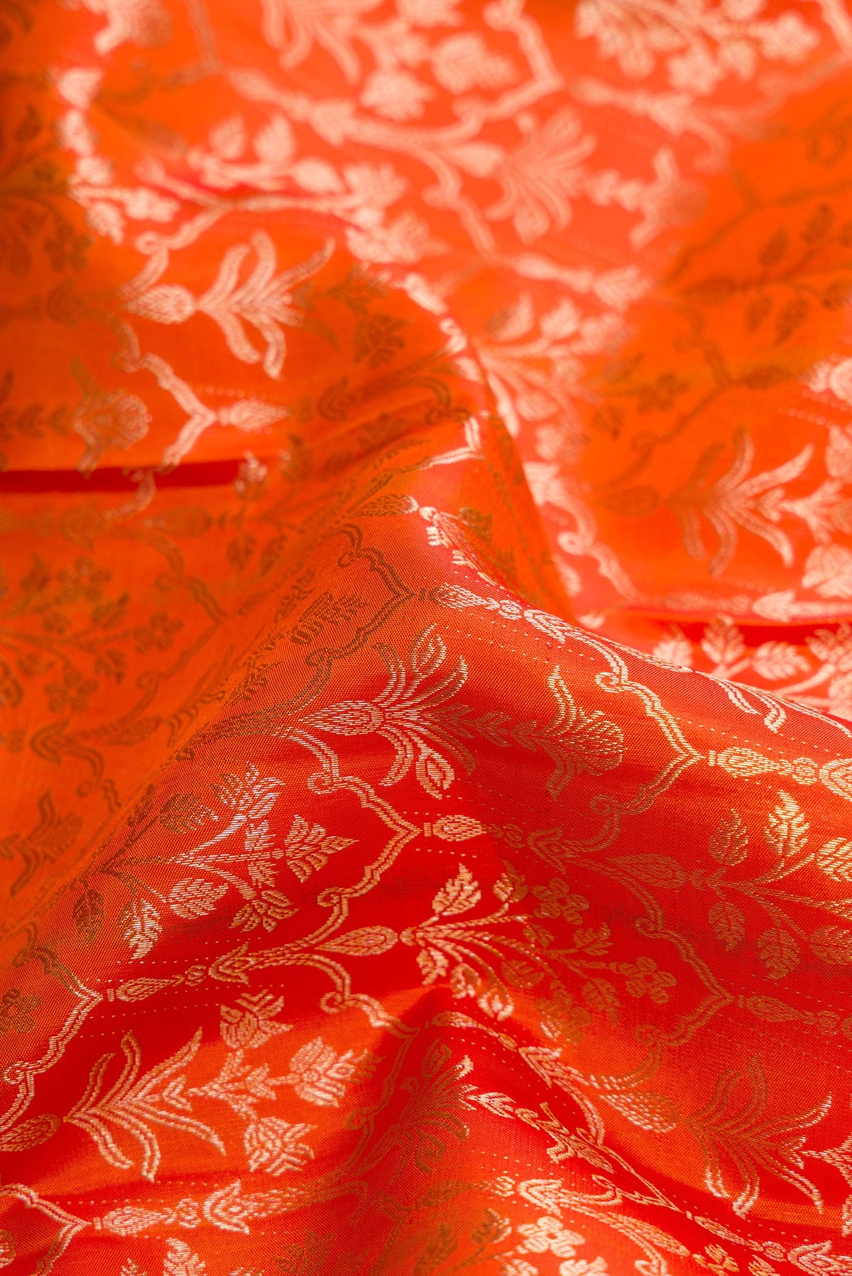 Close up of Orange Dual Tone Kanchipuram Silk Saree with Zari Brocade on the body and Zari Border.  displaying folds