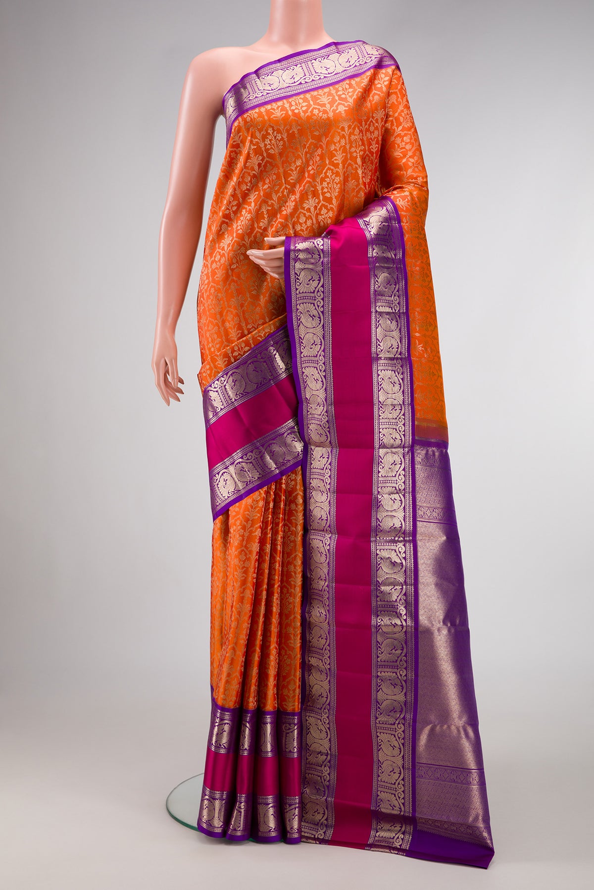 Orange Kanchipuram Silk Saree with Zari Brocade on the body and Zari Border.  displayed on a mannequin