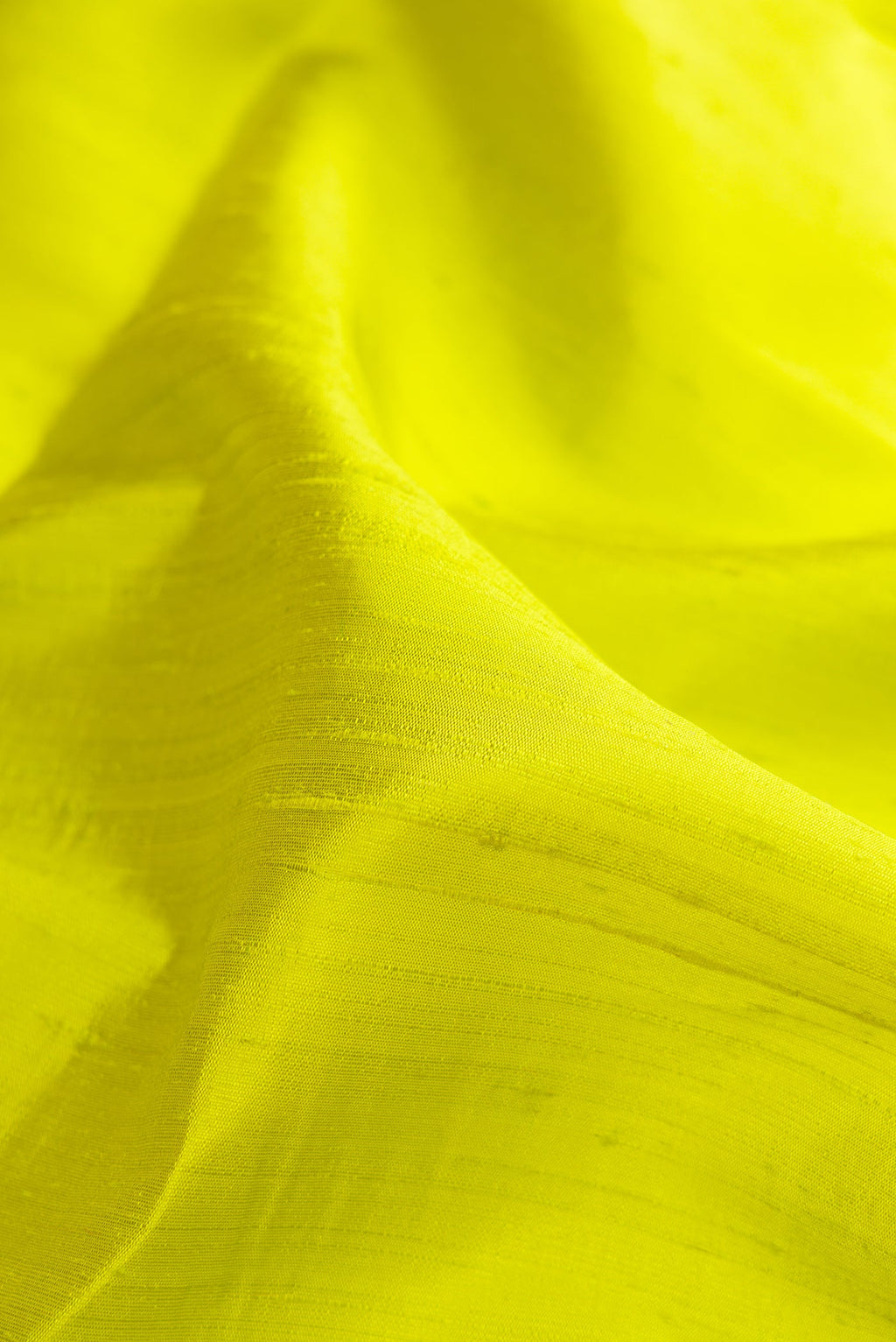 Close up of Parrot Green Raw Silk Saree with Plain Body and Zari Border.  displaying folds