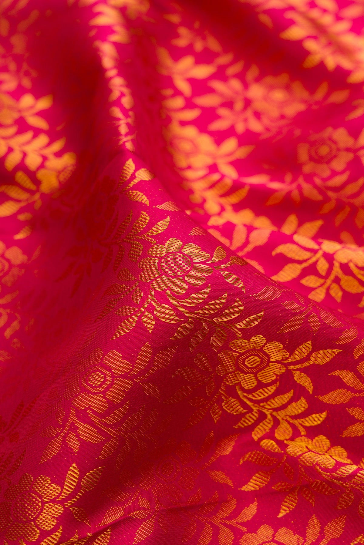 Close up of Dark Pink Kanjivaram Silk Saree with Zari Brocade on the body and Zari Border.  displaying folds