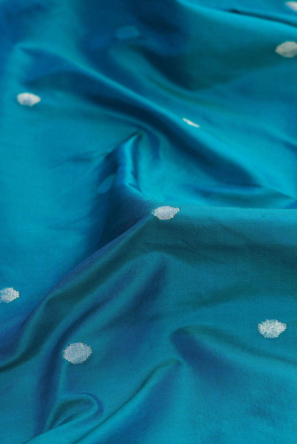 Close up of Pure Silk Pure Zari Peacock Blue Dual Tone Paithani Saree with Zari Butta on the body and Paithani Border.  displaying folds