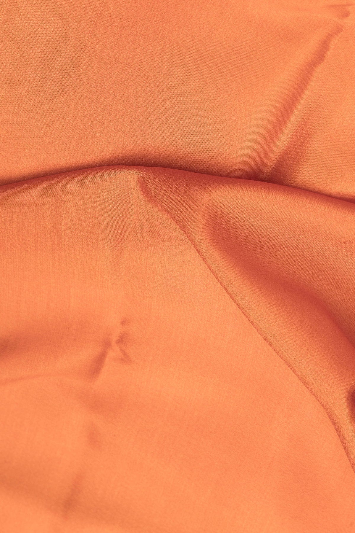 Close up of Brick Orange Mysore Crepe Saree with Plain Body and Zari Border.  displaying folds
