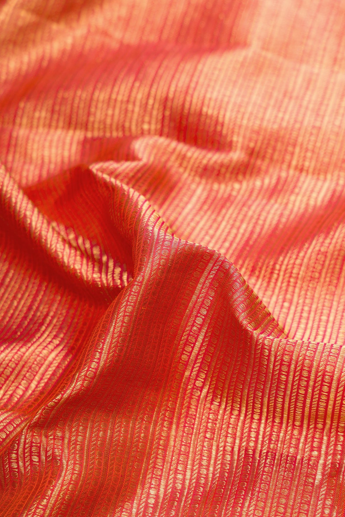 Close up of Coral Dual Tone Kanchipuram Silk Saree with Zari Brocade on the body and Zari Border.  displaying folds