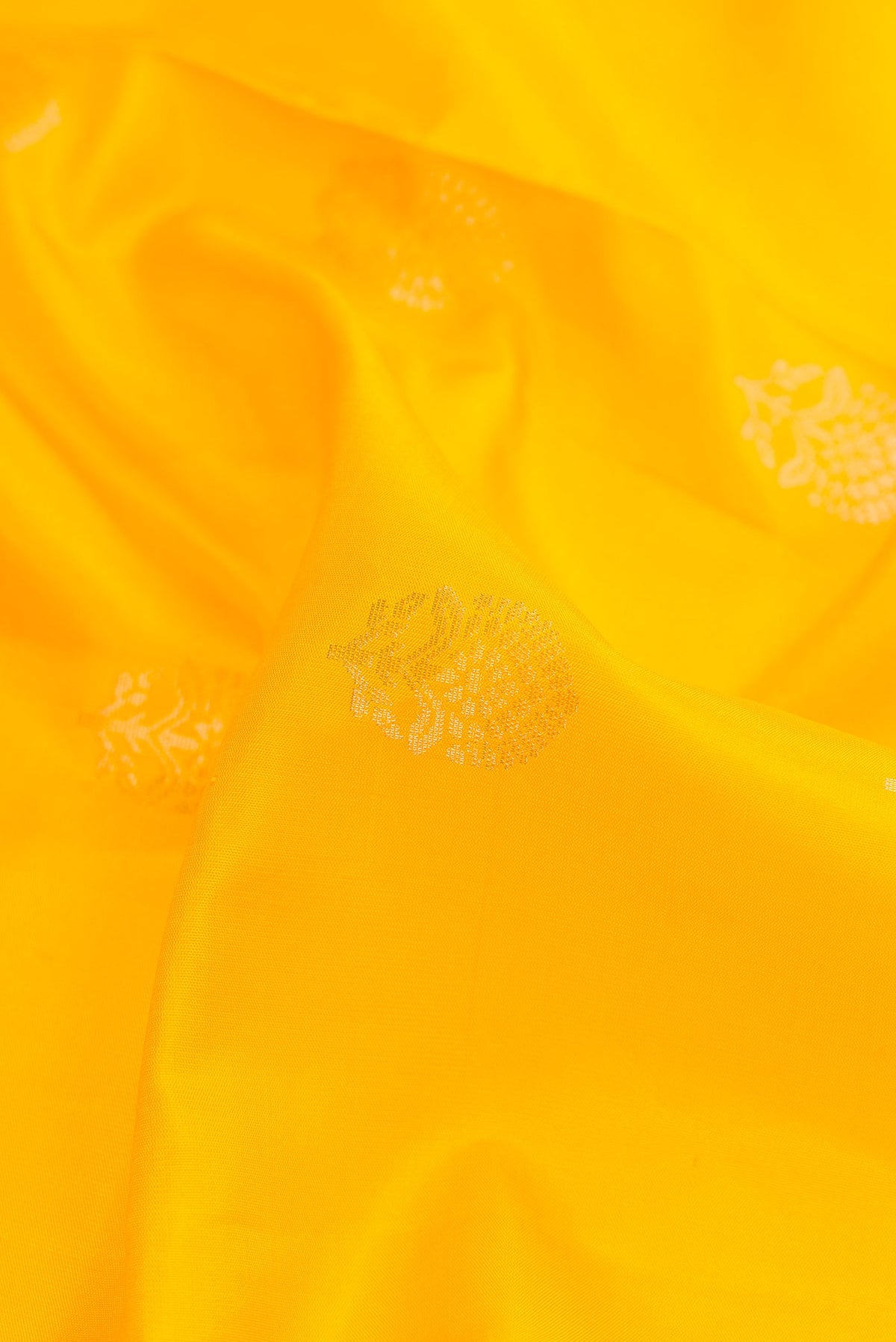 Close up of Yellow Dual Tone Soft Silk Saree with Zari Butta on the body and Zari Border.  displaying folds