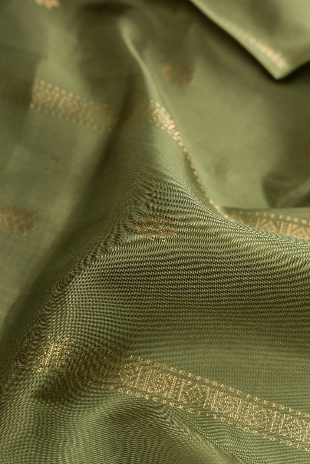 Close up of Mehandi Green Dual Tone Soft Silk Saree with Zari Butta on the body and Zari Border.  displaying folds