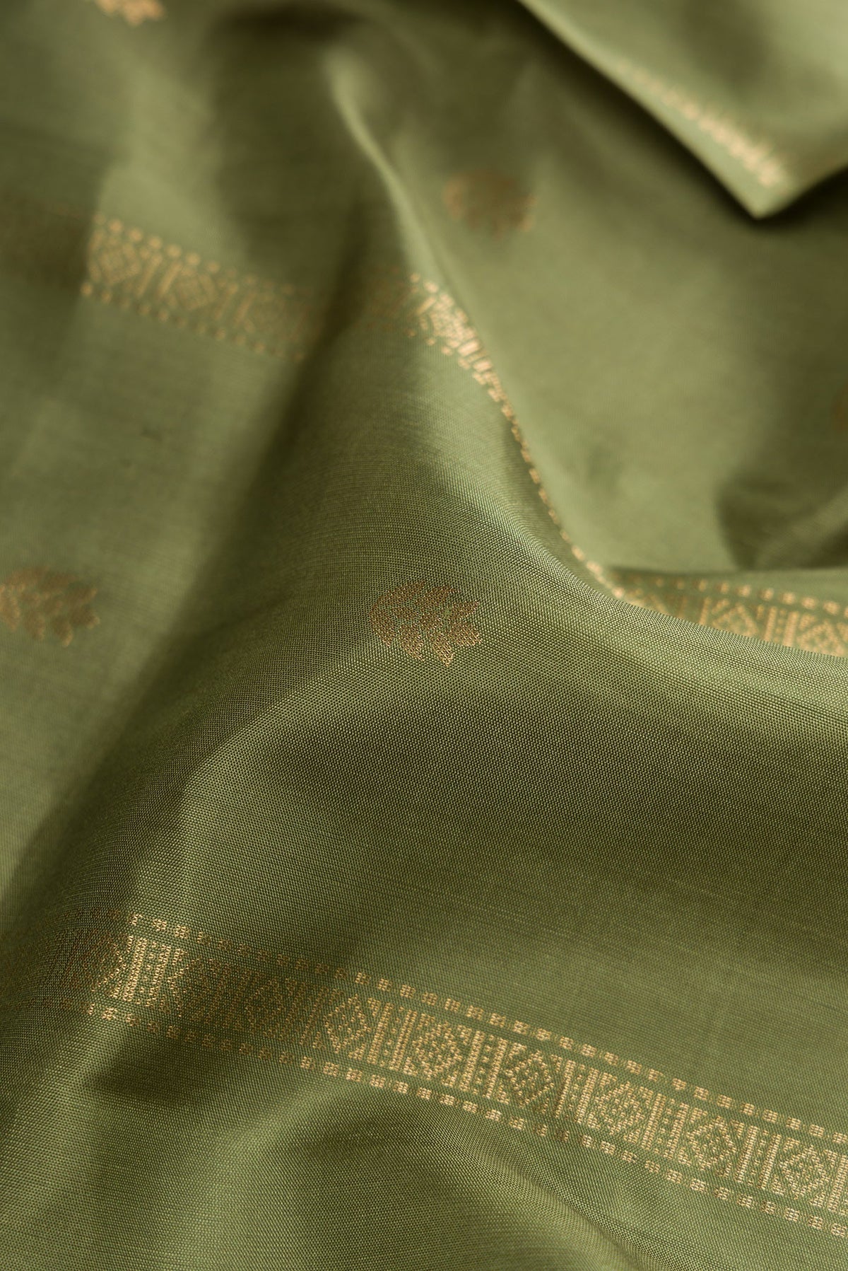 Close up of Mehandi Green Dual Tone Soft Silk Saree with Zari Butta on the body and Zari Border.  displaying folds