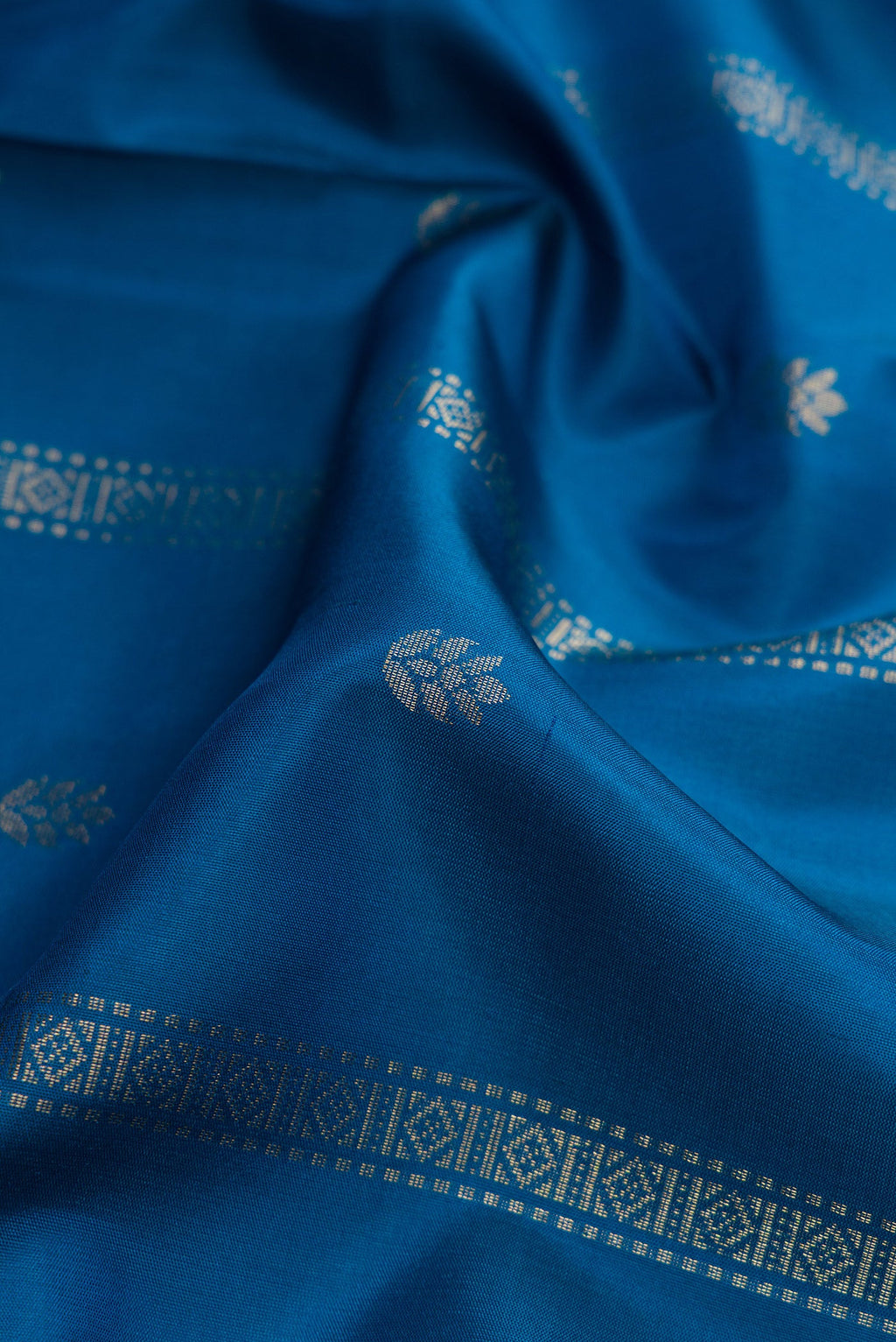 Close up of Peacock Blue Dual Tone Soft Silk Saree with Zari Butta on the body and Zari Border.  displaying folds