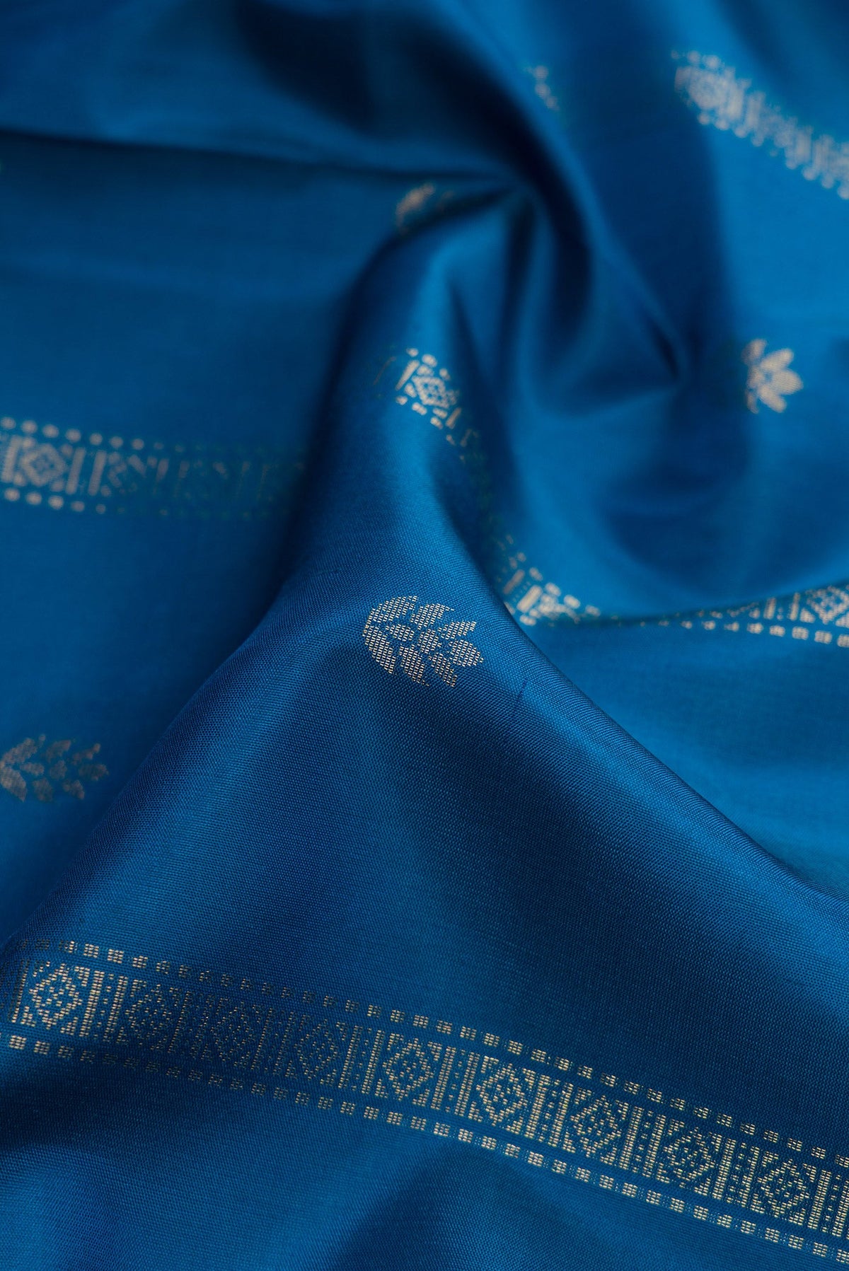 Close up of Peacock Blue Dual Tone Soft Silk Saree with Zari Butta on the body and Zari Border.  displaying folds