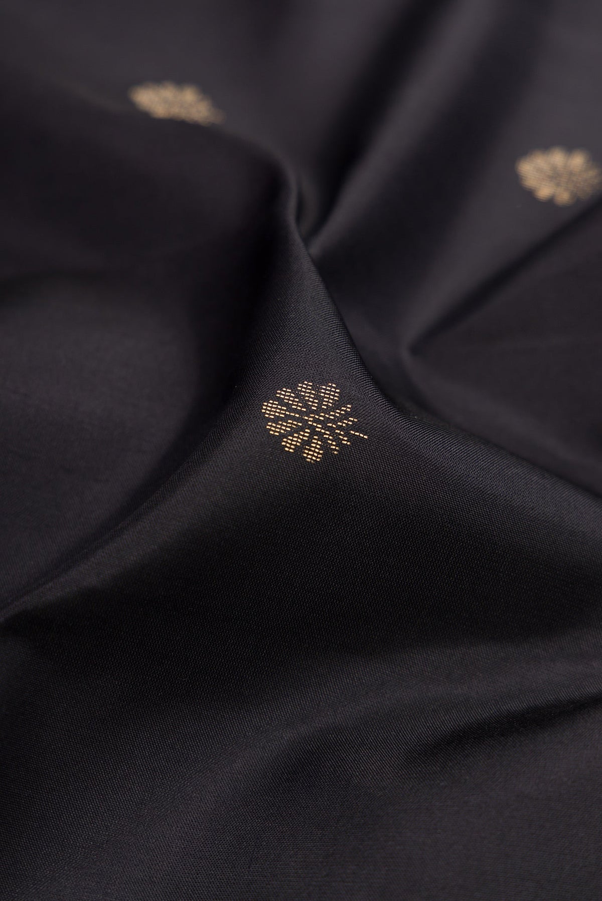 Close up of Black Soft Silk Saree with Zari Butta on the body and Fancy Border.  displaying folds