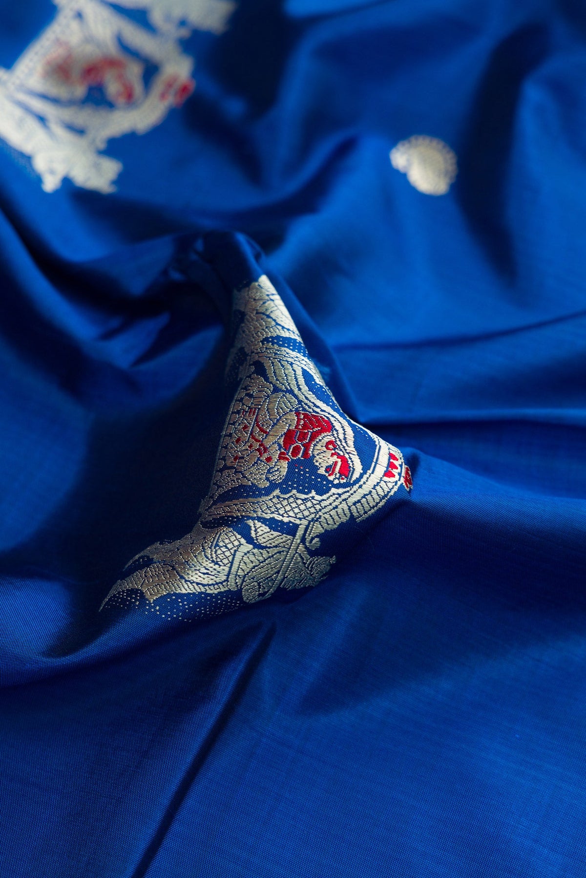Close up of Royal Blue Dual Tone Baluchari Silk Saree with Thread Butta on the body and Thread Border.  displaying folds